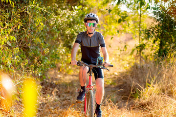 Cyclist riding a bike on a trail in the forest. He is wearing cycling gear and apparel. Inspirational image of a healthy lifestyle through cycling.