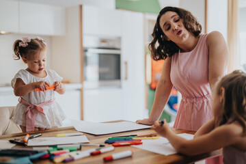 Young mother enjoying quality time drawing and painting with her little daughters at home. Family bonding, creative activities, and childhood moments.