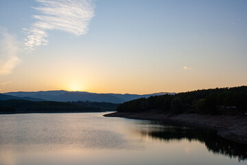 Sunset over a lake with mountains in the background and clouds in the sky. Sunset over a lake with mountains in the background. Lake landscape
