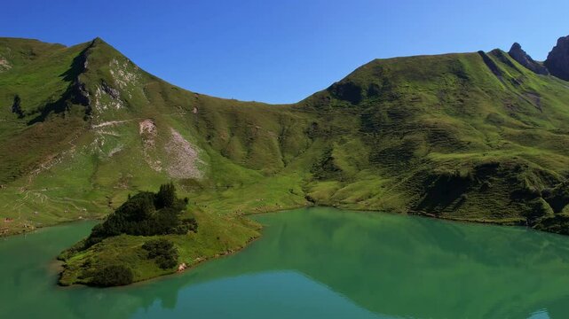 4K Aerial Drone video of the most beautiful mountain lake Schrecksee in Bavarian Alps with the cows feeding on lush green grass on a sunny day with blue skies and rocky hill tops surrounding