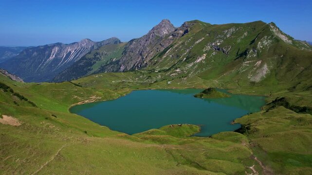 4K Aerial Drone video of the most beautiful mountain lake Schrecksee in Bavarian Alps with the cows feeding on lush green grass on a sunny day with blue skies and rocky hill tops surrounding
