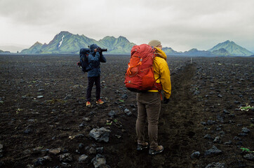 Two hikers on a volcanic lava trail stopping to take photos in Iceland