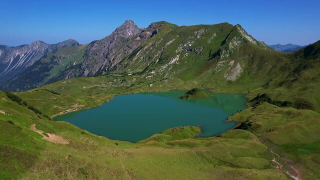 4K Aerial Drone video of the most beautiful mountain lake Schrecksee in Bavarian Alps with the cows feeding on lush green grass on a sunny day with blue skies and rocky hill tops surrounding