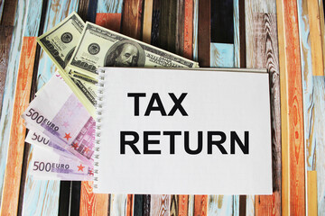 Notepad with text tax return on dollars and euros
