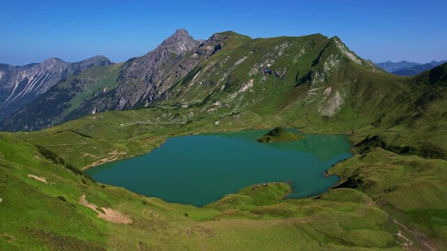 4K Aerial Drone video of the most beautiful mountain lake Schrecksee in Bavarian Alps with the cows feeding on lush green grass on a sunny day with blue skies and rocky hill tops surrounding