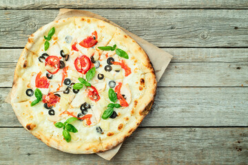 Pizza with mozzarella cheese , olives , chicken , pineapple , basil and tomatoes