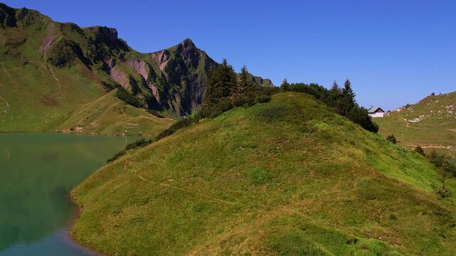 4K Aerial Drone video of the most beautiful mountain lake Schrecksee in Bavarian Alps with the cows feeding on lush green grass on a sunny day with blue skies and rocky hill tops surrounding