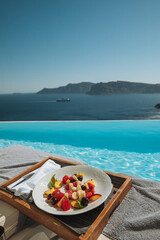 Infinity pool with view of volcano caldera in Santorini, Geece and a fruit salad
