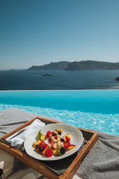 Infinity pool with view of volcano caldera in Santorini, Geece and a fruit salad