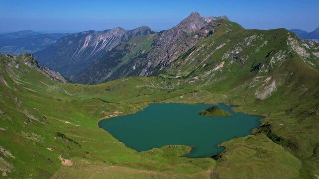 4K Aerial Drone video of the most beautiful mountain lake Schrecksee in Bavarian Alps with the cows feeding on lush green grass on a sunny day with blue skies and rocky hill tops surrounding