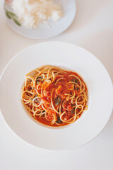 pasta with cherry tomatoes on white plate. Plate of delicious Italian spaghetti pasta with fresh basil leaves, with tomato sauce, vegetables