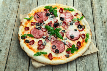 Pizza with mozzarella cheese , salami sausages , olives , and basil