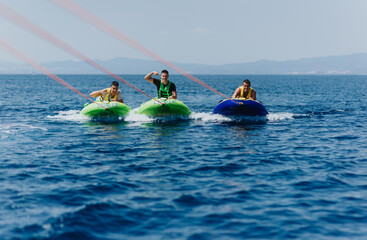 Group of friends enjoying speedboat tubing adventure on a sunny day at the sea