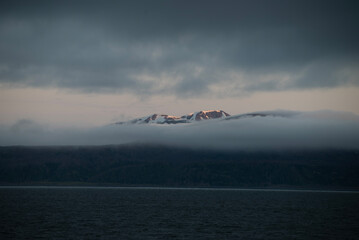 A bay surrounded by snow-capped mountains and dotted with ice formations. The magic of nature in its frozen splendor. A unique combination of ice and sea.Travel in cold weather, fresh air
