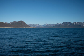 A bay surrounded by snow-capped mountains and dotted with ice formations. The magic of nature in its frozen splendor. A unique combination of ice and sea.Travel in cold weather, fresh air