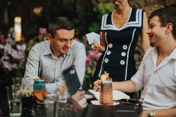 Group of colleagues gathered for a team meeting in a lush garden setting, surrounded by colorful flowers. Casual, collaborative atmosphere promoting discussion and teamwork.
