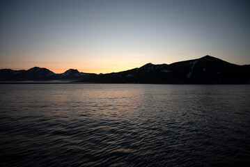 Fototapeta premium Stunning sunset over mountains and sea on wild natural islands in the northern region of the world, a journey to the cold and fiery sunsets of nature
