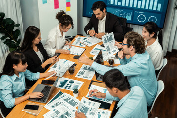 Diverse group of business analyst team analyzing financial data report. Finance data analysis chart and graph dashboard show on TV screen in meeting room for strategic marketing planning. Habiliment