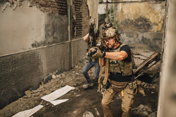 Fototapeta premium Troops waking towards camera in ruins with weapon and going in battle.