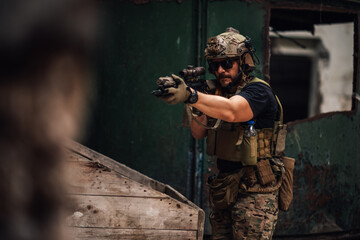 Fototapeta premium Portrait of soldier shooting with sniper rifle toward camera in ruins.