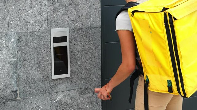 unrecognized hispanic food delivery girl with yellow backpack ringing doorbell at customer&rsquo;s house