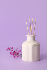 Floral reed diffuser and flowers on purple background