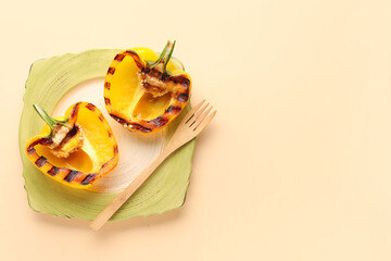 Plate with halves of tasty grilled bell pepper on beige background