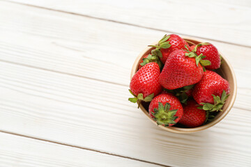 Bowl with fresh strawberries on white wooden background
