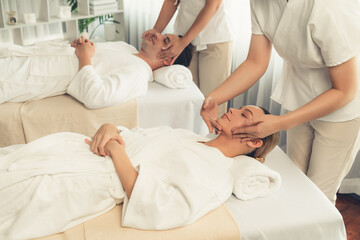 Fototapeta premium Caucasian couple enjoying relaxing anti-stress head massage and pampering facial beauty skin recreation leisure in dayspa modern light ambient at luxury resort or hotel spa salon. Quiescent