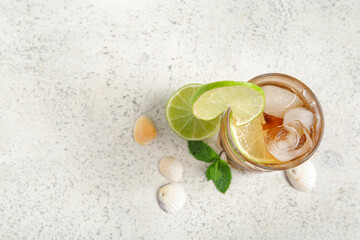 Glass of cold Cuba Libre cocktail and seashells on white background