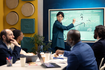 Chief financial officer presenting capital funds and revenue data on annual reports in a conference room, reviewing profit increase and budget allocation for a project. Informative meeting.