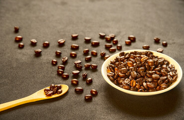 Close-up, coffee beans on a black background, wooden spoon