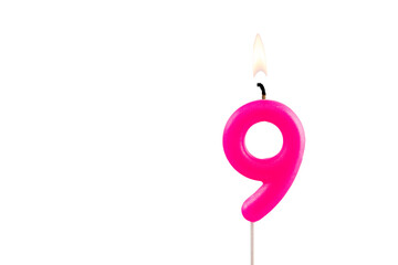 Pink number 9 birthday candle lit on white background