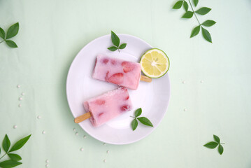 Close-up of two strawberry ice cream with lemon and green leaves, top view