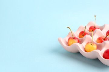 Ice cube tray with sweet yellow cherries on blue background