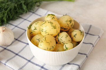 Bowl with boiled baby potatoes on light background