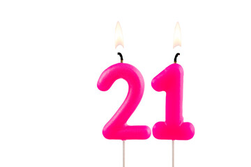 Pink number 21 birthday candle lit on white background