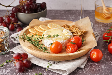 Plate of tasty baked Camembert cheese on grey background