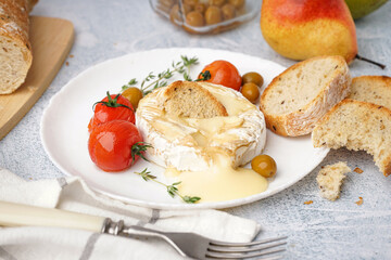 Plate of tasty baked Camembert cheese on light background