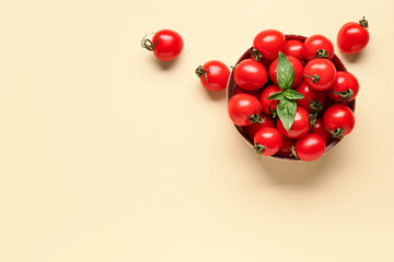 Bowl with fresh cherry tomatoes and basil on orange background
