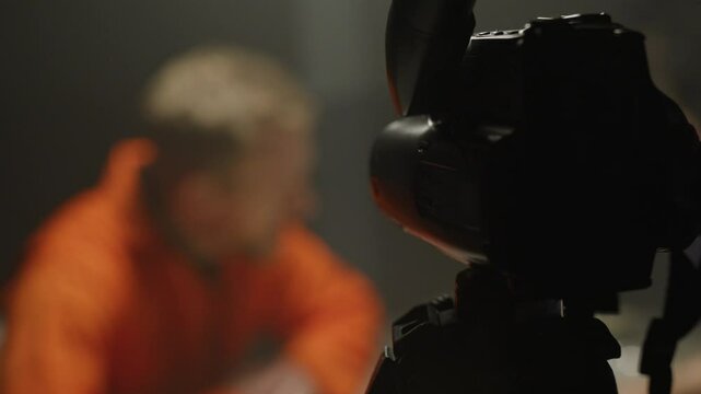 Zoom out to camera recording testimony from police suspect