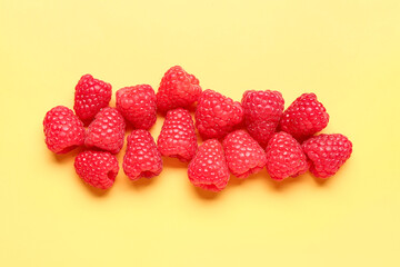 Many fresh raspberries on yellow background