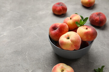 Bowl with sweet fig peaches and mint on grey background