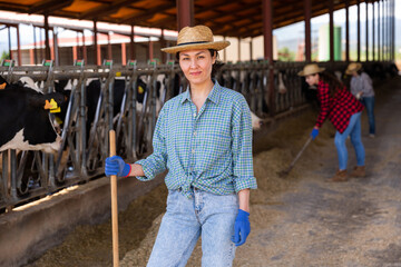 Portrait of positive female farm worker in a cowshed