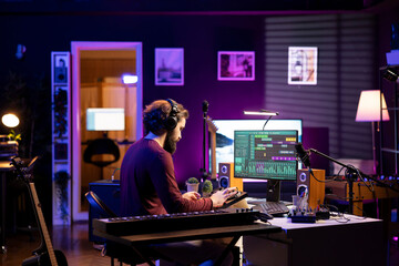 Music producer working on editing soundtracks and audio recordings with daw software interface on...