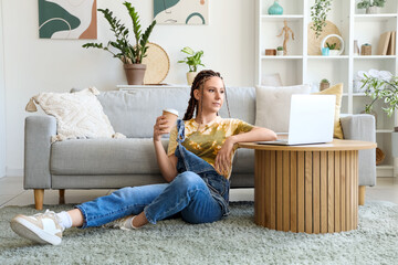 Young woman with dreadlocks and laptop at home