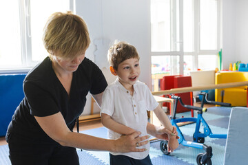 Male child with cerebral palsy receives support during a physical therapy session focused on...