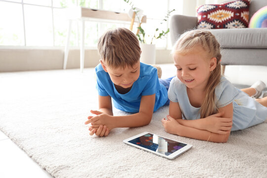 Cute little children watching cartoons on tablet computer at home