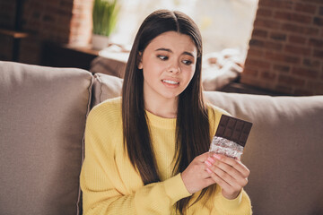 Photo portrait of attractive teen woman look scared disgusted chocolate bar dressed yellow outfit...