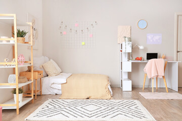 Interior of light teenager's room with bed, shelf unit and study table